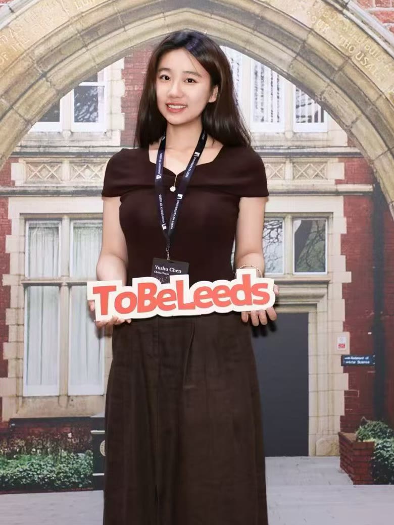 Yushu Chen at a University of Leeds recruitment event in China, wearing a China Team name badge and holding a ToBeLeeds sign.